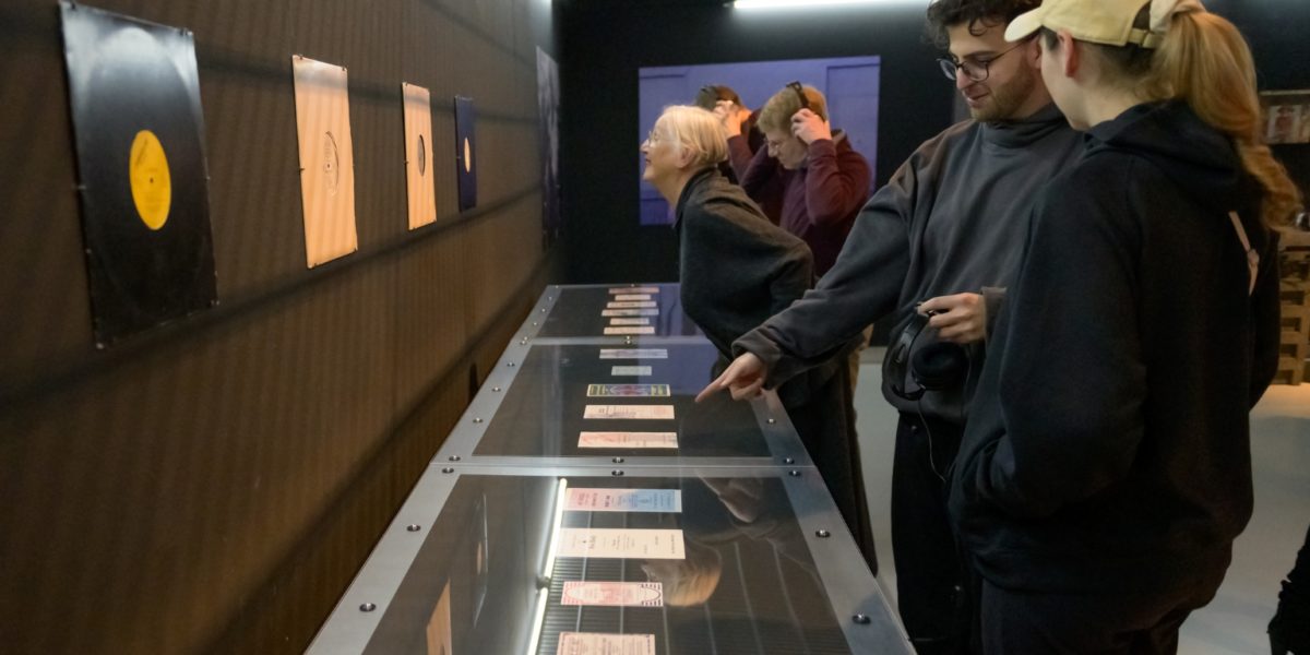 Op een tafel liggen flyers van de eerste clubs, twee mensen kijken hiernaar en wijzen.