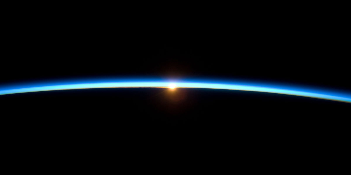 De ronding van de aarde gezien vanaf de ruimte, terwijl de zon ondergaat.