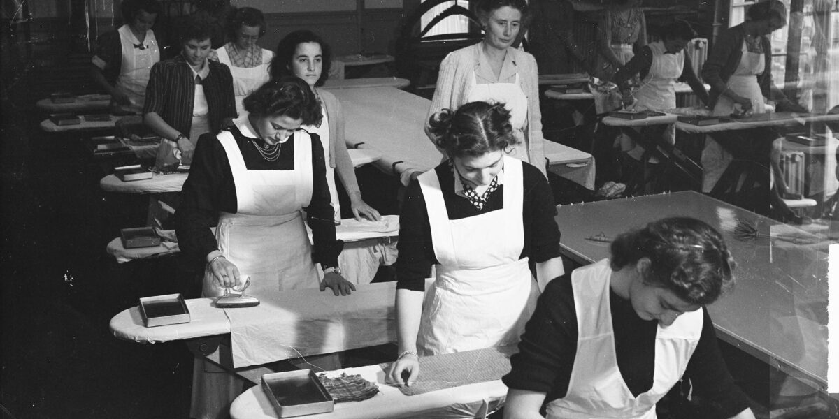 Historische foto. Meisjes krijgen les in strijken op de Amsterdamse Huishoudschool.